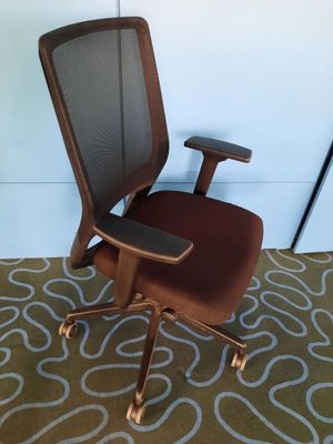 une chaise de bureau marron avec une assise marron, posée sur un tapis