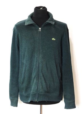 un pull vert à fermeture éclair posé sur un mannequin, sur fond blanc