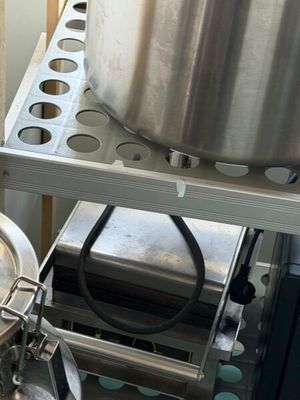 Les casseroles et les poêles sont rangées sur une étagère dans une cuisine, à côté d'une cuisinière.