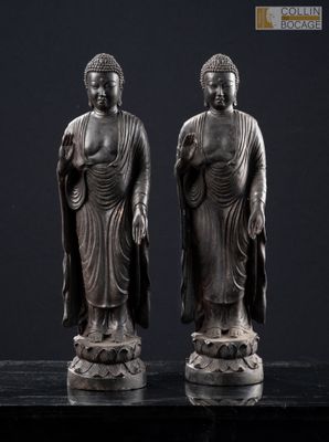 deux statues de bouddhas assis sur une surface noire