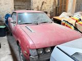 two old cars parked in a garage next to each other