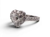 un gros plan d'une bague en diamant en forme de cœur sur fond blanc