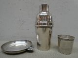 un shaker en argent et une coupe en argent posés sur une table