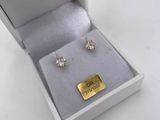 a pair of earrings in a white box with a gold plate
