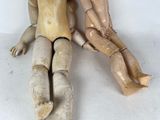 two wooden dolls sitting next to each other on the floor