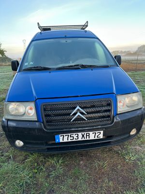 La camionnette bleue est garée sur l'herbe, dans le champ.