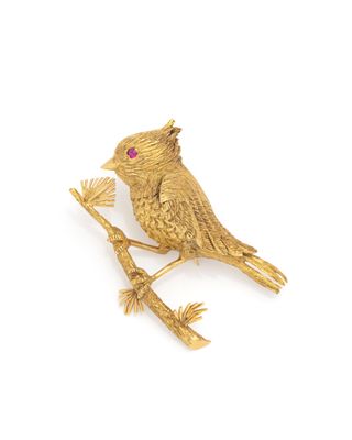 gold plated bird brooch with ruby eyes on a branch