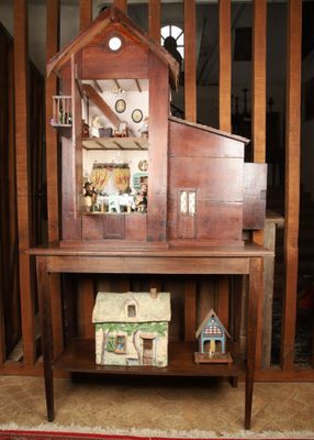 une maison de poupées posée sur une table sur laquelle se trouve une autre maison de poupées
