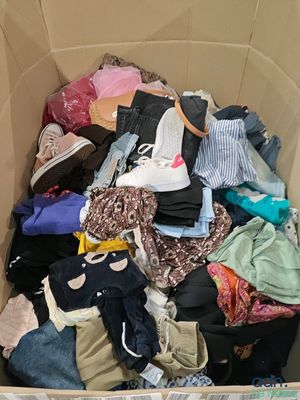 a cardboard box full of clothes and clothing on the floor