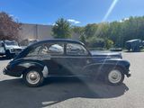 an old black car parked in a parking lot next to a building