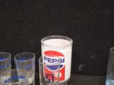 bottles and glasses are lined up on a table with a can of pepsi