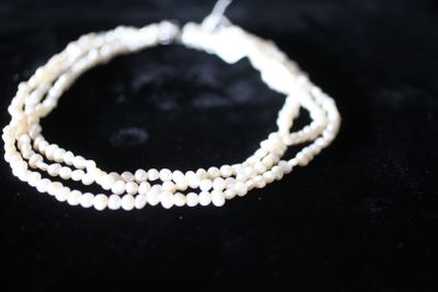 un gros plan sur trois rangées de perles de verre blanches sur une surface noire
