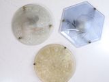 trois assiettes en verre posées sur une table blanche, éclairées par une lampe
