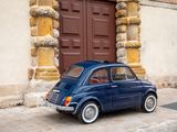a small blue car that is parked in front of a building