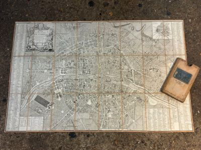 an old map of the city of paris with a book on the ground