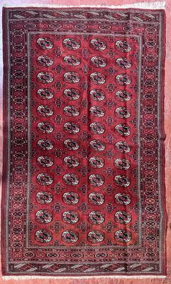 tapis oriental rouge et noir exposé dans une pièce