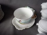 a cup and saucer sitting on a table next to a stack of plates