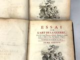 trois livres ouverts posés sur une table, avec une étiquette dessus
