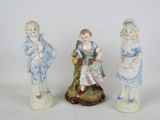 trois figurines d'enfants vêtus de tenues bleues et blanches