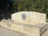 un banc en pierre au milieu d'un champ de terre battue