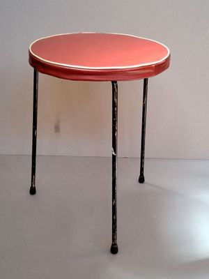 a small table with a red top sitting on a white floor