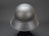 an old metal helmet on a black stand against a gray background