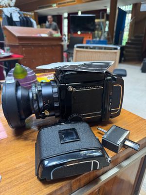 a black camera sitting on top of a table next to a cell phone