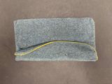 grey felt pouch with yellow thread on top of it