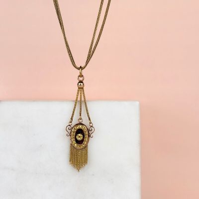 a gold and black necklace with a tassel hanging from it
