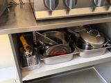 des casseroles et des poêles sont posées sur une étagère dans une cuisine