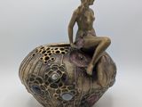 statue d'une femme assise au sommet d'un objet décoratif