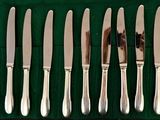 six knives in a row on a green cloth