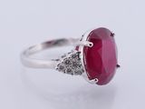 a close up of a ring with a red stone surrounded by white diamonds