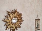 un soleil doré accroché au mur à côté d'un miroir