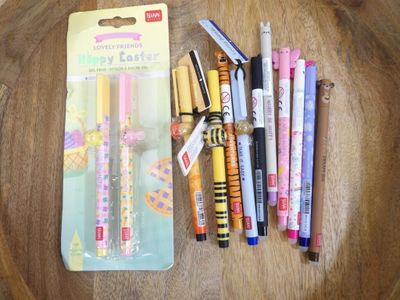 de nombreux stylos et feutres de différentes couleurs posés sur une table en bois
