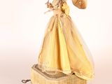 a figurine of a woman in a yellow dress holding an umbrella