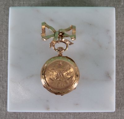 a small gold pocket watch with a bow on it