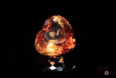 a close up of a heart shaped orange diamond on a black surface