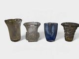 four different colored glass vases sitting next to each other on a white surface