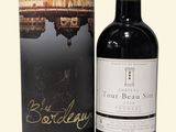 La bouteille de vin rouge se trouve à côté d'un carton.