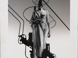 black and white photograph of a woman in a dress standing next to a machine
