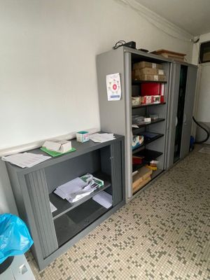 un réfrigérateur dans un coin de la pièce, à côté d'une bibliothèque