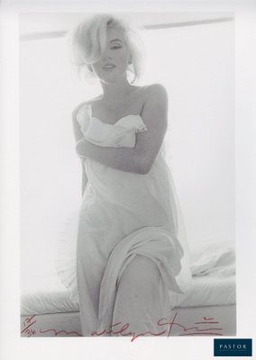 an old photo of a woman in a white dress sitting on a bed