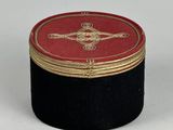 a small black box with a red lid on a white surface