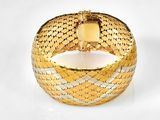 une image d'un gros plan d'un bracelet en or sur une surface blanche
