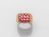 a gold ring with pink stones on a white surface