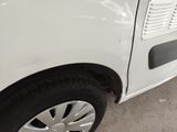 a small white car with a flat tire parked in a parking lot