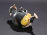 a teapot shaped like a fish with a spoon in the shape of a fish
