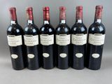 six bottles of wine are lined up in a row on a table