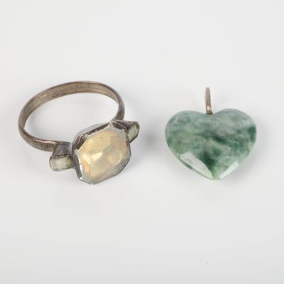 deux anneaux et une pierre en forme de coeur sur une surface blanche